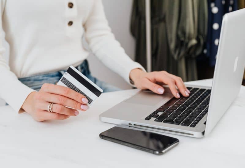 femme avec sa carte bleu dans les mains sur son pc