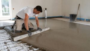 ouvrier qui pose une chape de beton